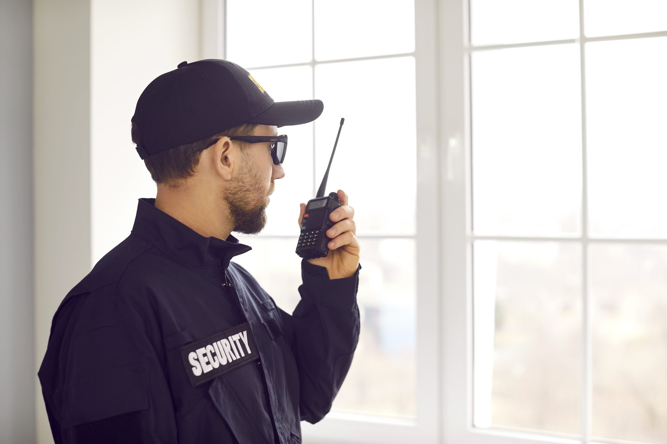 Security guard using radio near window.